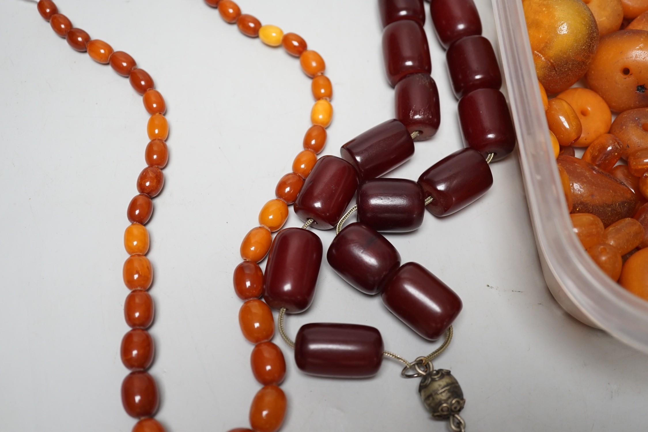 A single strand graduated amber bead necklace, 54cm gross weight 30 grams, together with loose amber beads, gross 153 grams and a simulated cherry amber necklace.